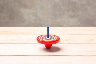 Photo of Bright spinning top on light wooden table