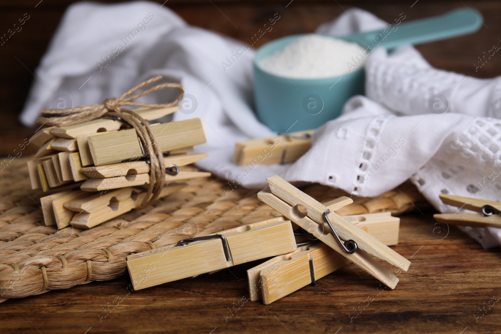 Photo of Wooden clothespins, scoop of laundry powder and fabric on table