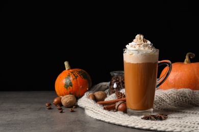 Glass cup with tasty pumpkin spice latte on gray table. Space for text