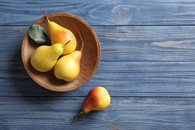 Photo of Plate with ripe pears on blue wooden background, top view. Space for text