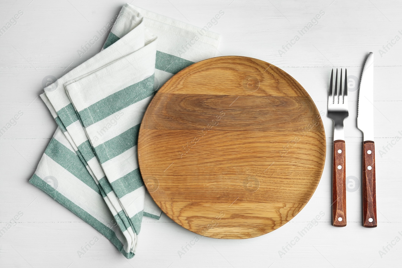 Photo of Empty wooden plate with cutlery and napkin on white table, flat lay