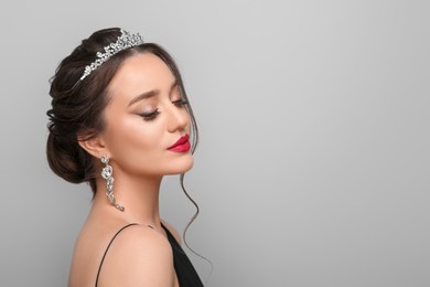 Photo of Beautiful young woman wearing luxurious tiara on light grey background, space for text