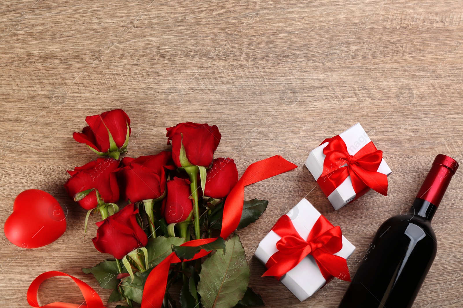 Photo of Flat lay composition with beautiful red roses and gift boxes on wooden background, space for text. Valentine's Day celebration