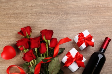 Flat lay composition with beautiful red roses and gift boxes on wooden background, space for text. Valentine's Day celebration