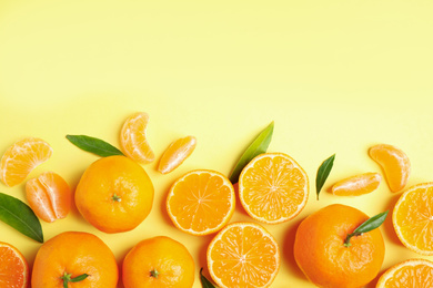 Flat lay composition with fresh ripe tangerines and leaves on light yellow background, space for text. Citrus fruit