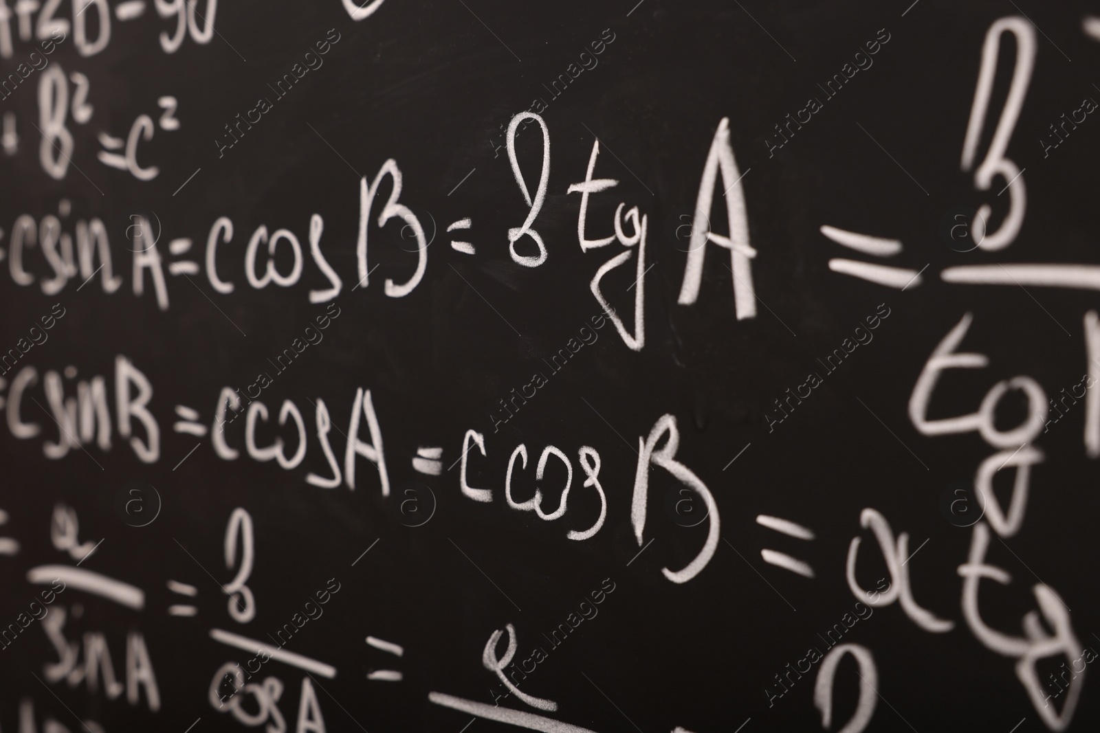 Photo of Different mathematical formulas written with chalk on blackboard, closeup