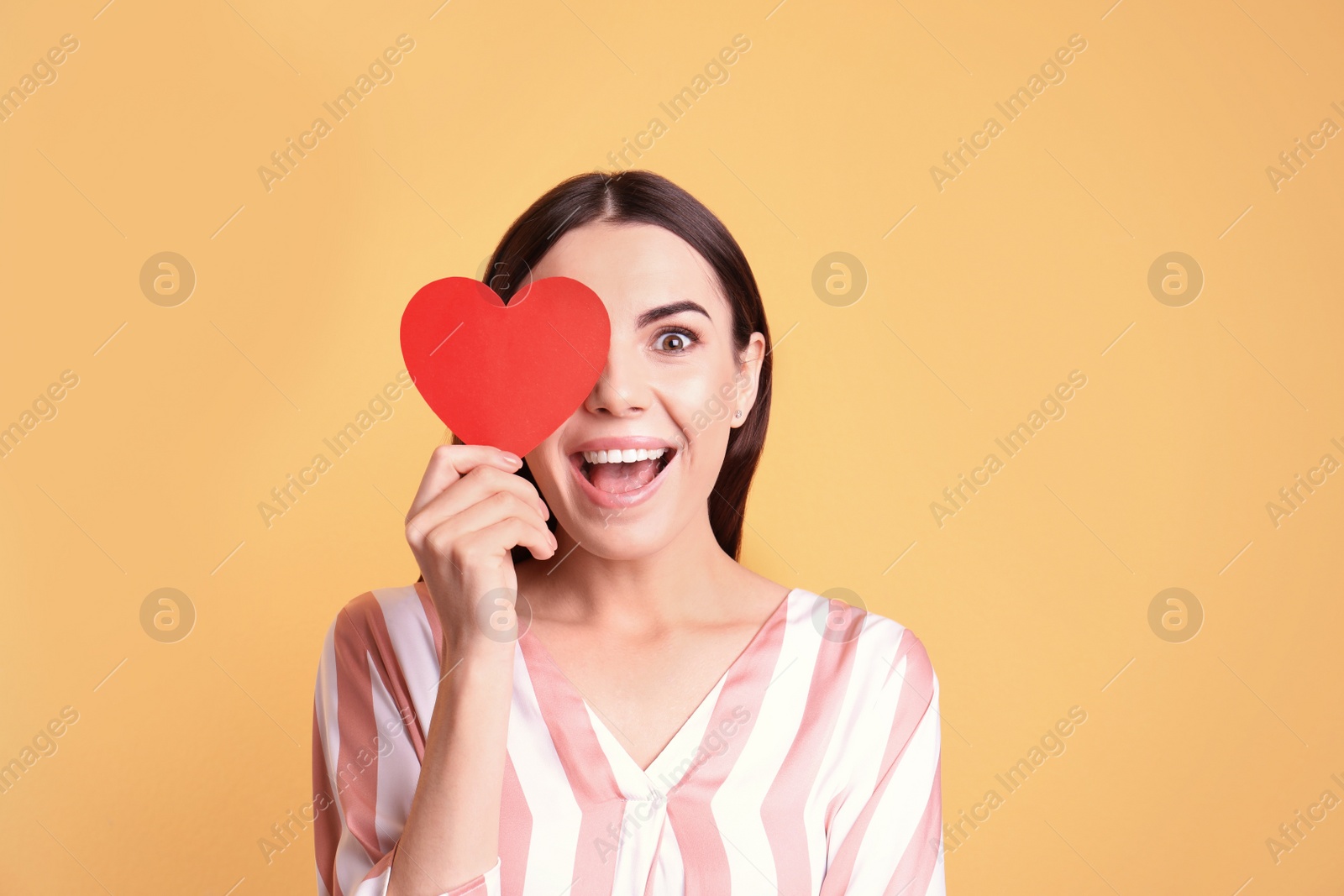 Photo of Portrait of young woman with paper heart on color background