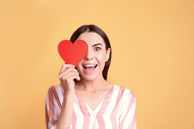 Photo of Portrait of young woman with paper heart on color background
