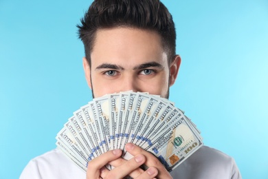 Portrait of happy young man with money on color background