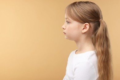 Photo of Hearing problem. Little girl on pale brown background, space for text