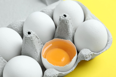 Photo of Fresh chicken eggs in box on yellow background, closeup