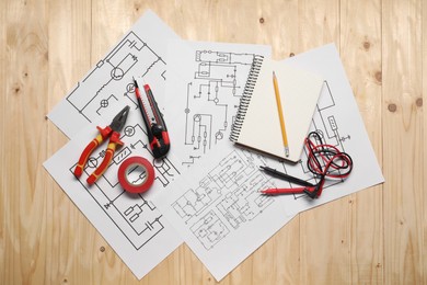 Photo of Wiring diagrams, tools and office stationery on wooden table, top view