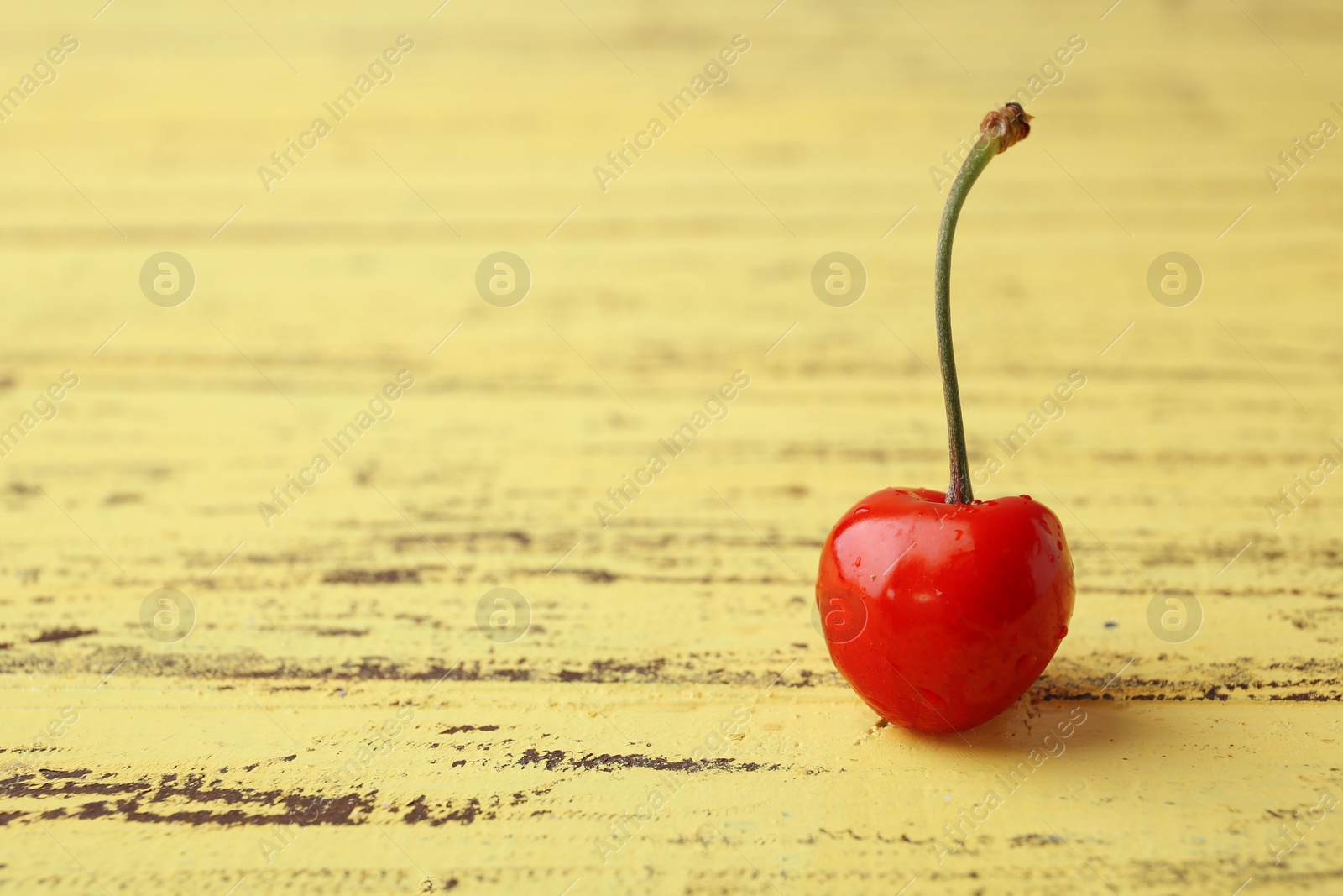 Photo of Ripe red cherry on yellow wooden background