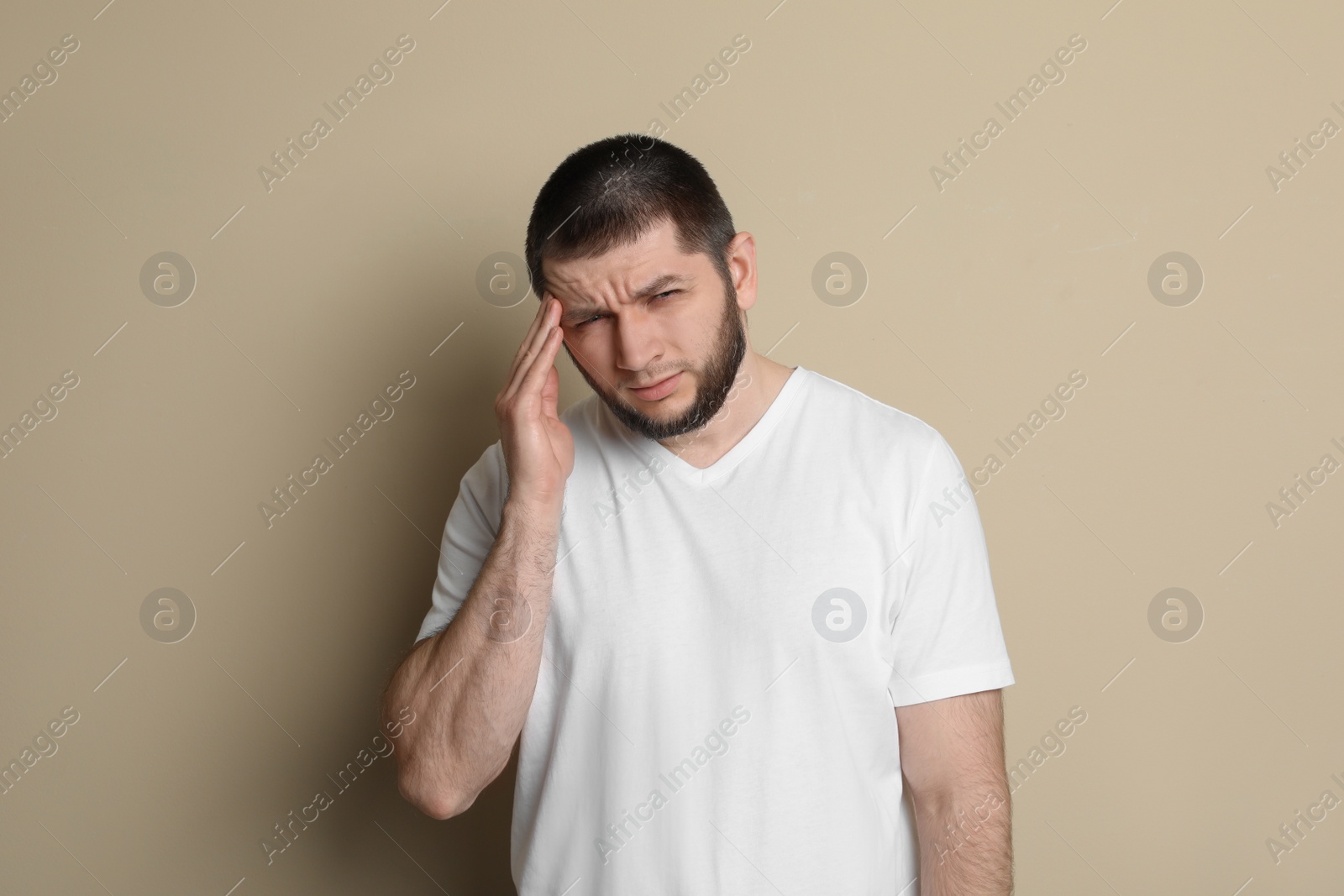 Photo of Man suffering from headache on beige background