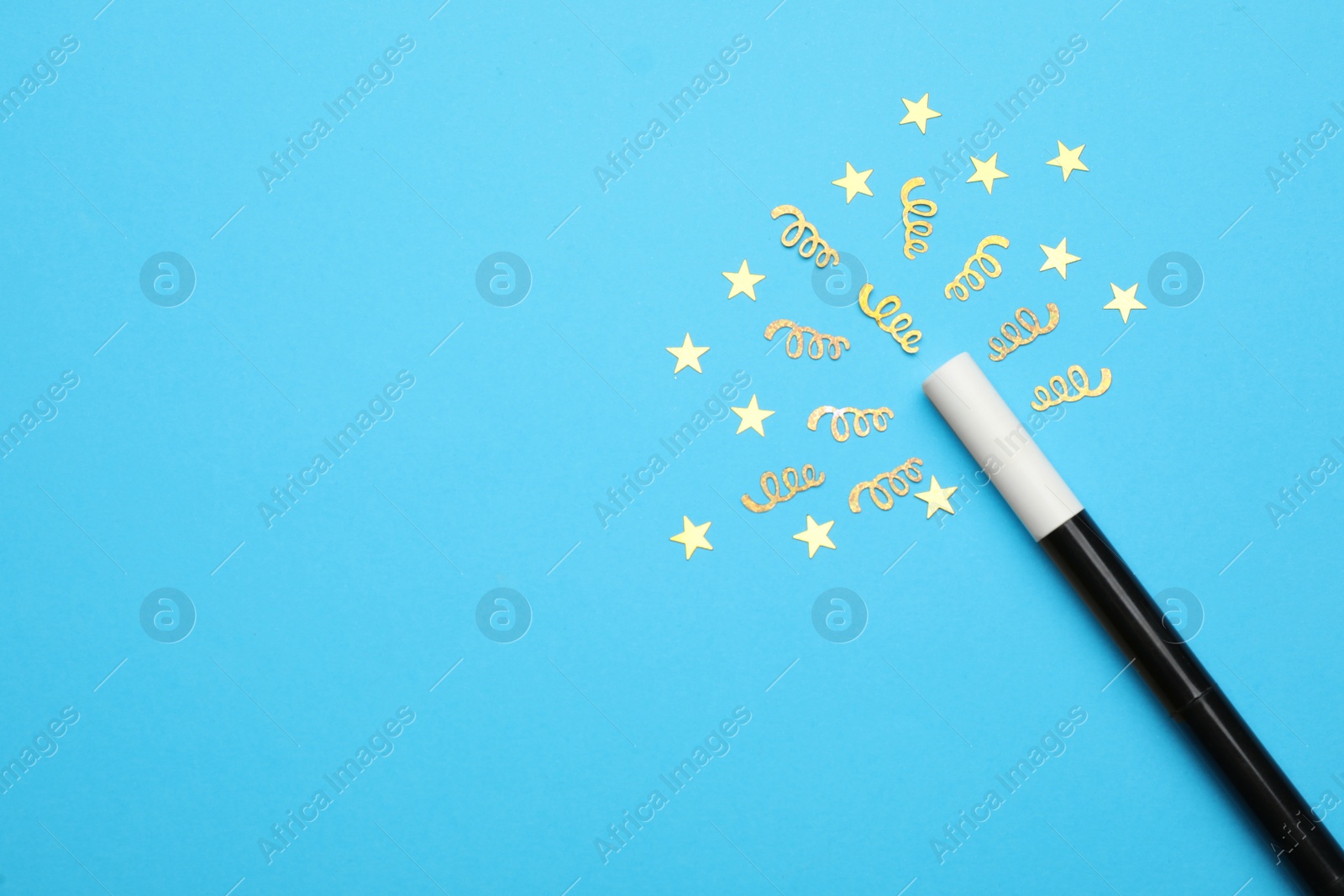 Photo of Beautiful black magic wand and confetti on light blue background, flat lay. Space for text