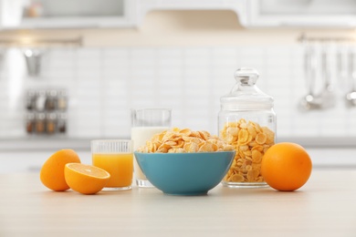 Cornflakes with glasses of juice and milk on kitchen table