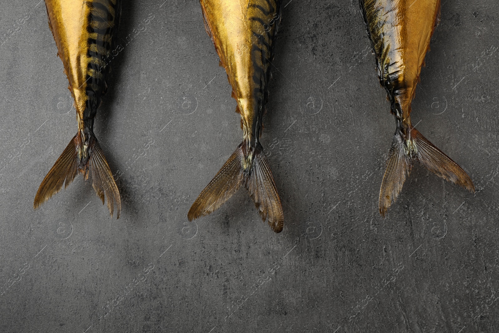 Photo of Tasty golden smoked fish on grey table, flat lay
