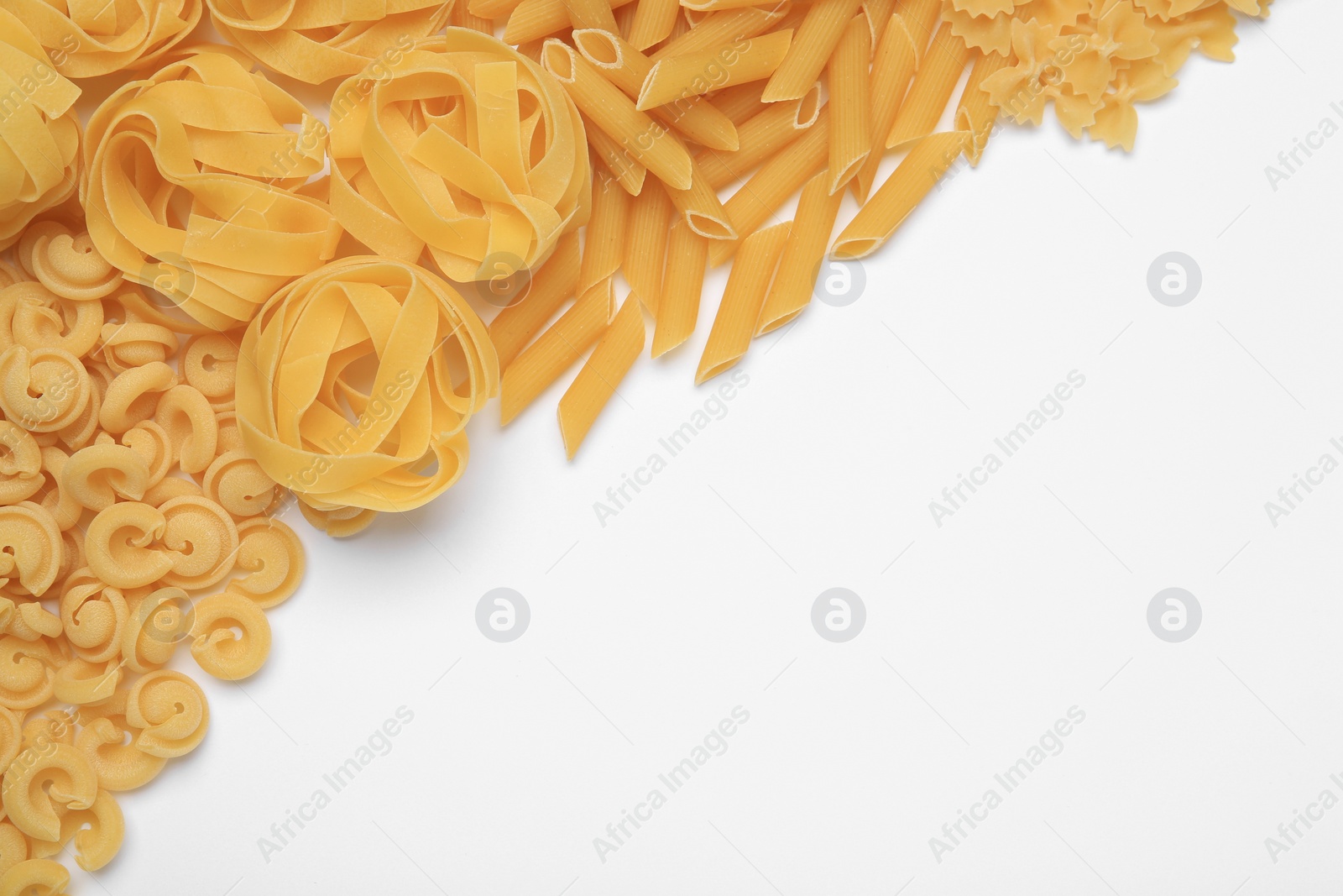 Photo of Different types of pasta on white background, flat lay. Space for text