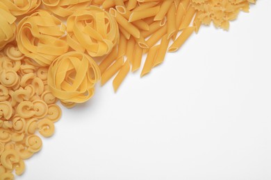 Different types of pasta on white background, flat lay. Space for text