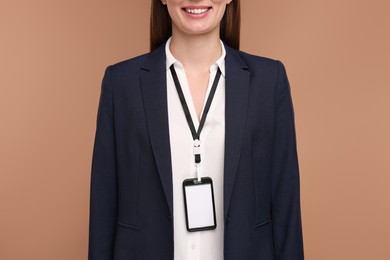 Photo of Woman with blank badge on light brown background, closeup