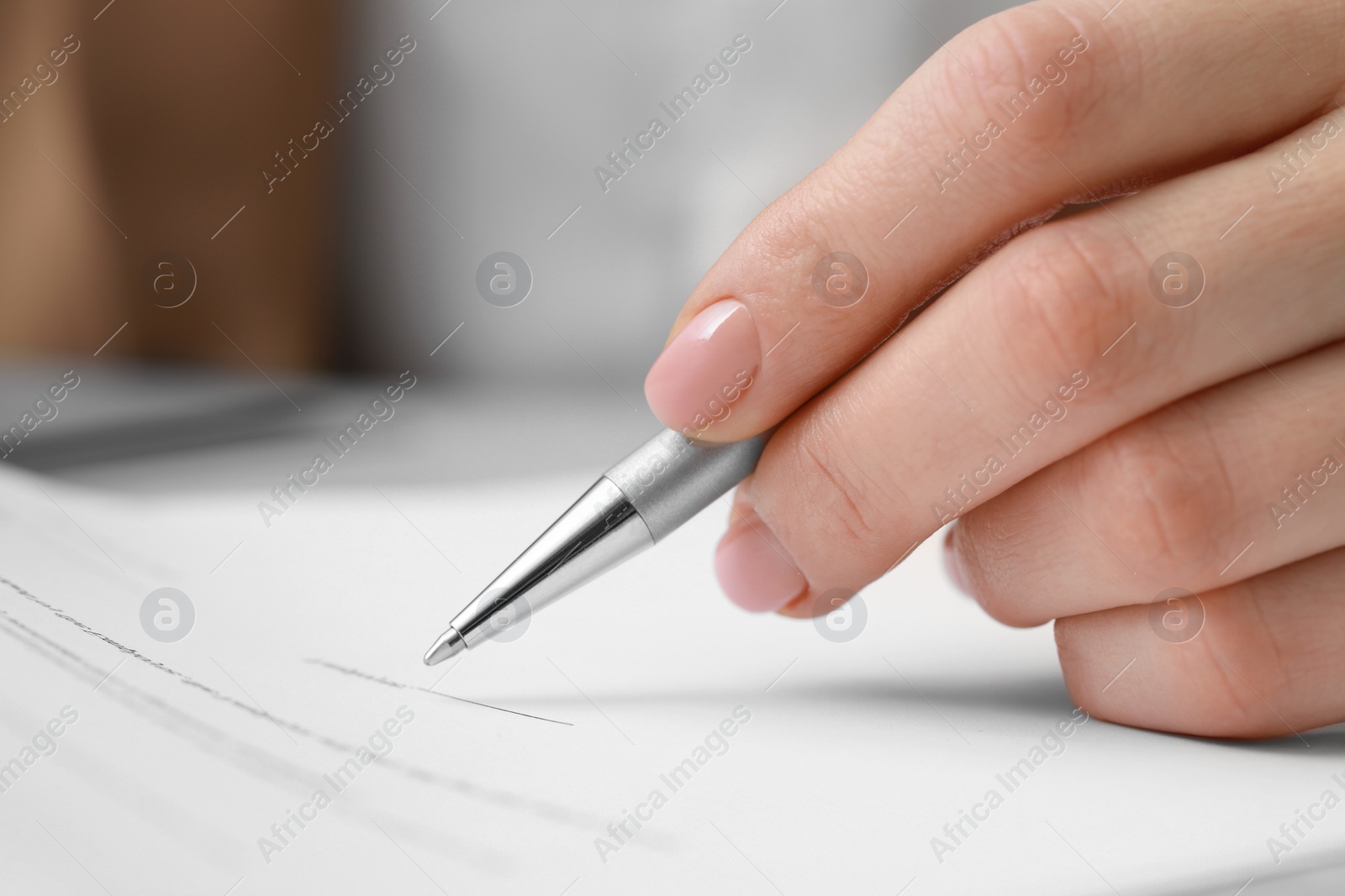 Photo of Closeup view of woman signing document at table