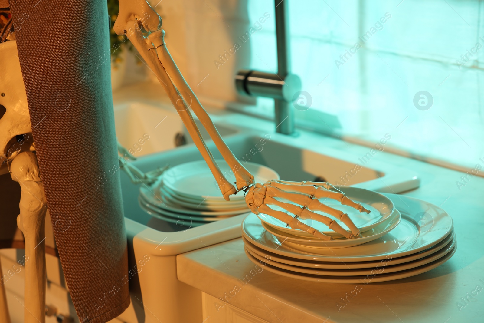 Photo of Human skeleton washing dishes in kitchen sink at night, closeup