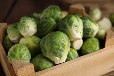 Photo of Fresh Brussels sprouts in wooden crate, closeup