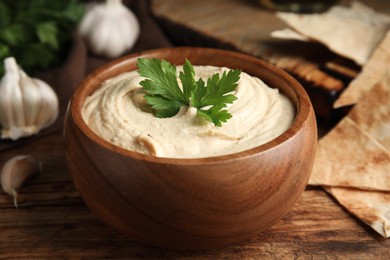 Delicious hummus and pita chips on wooden table, closeup