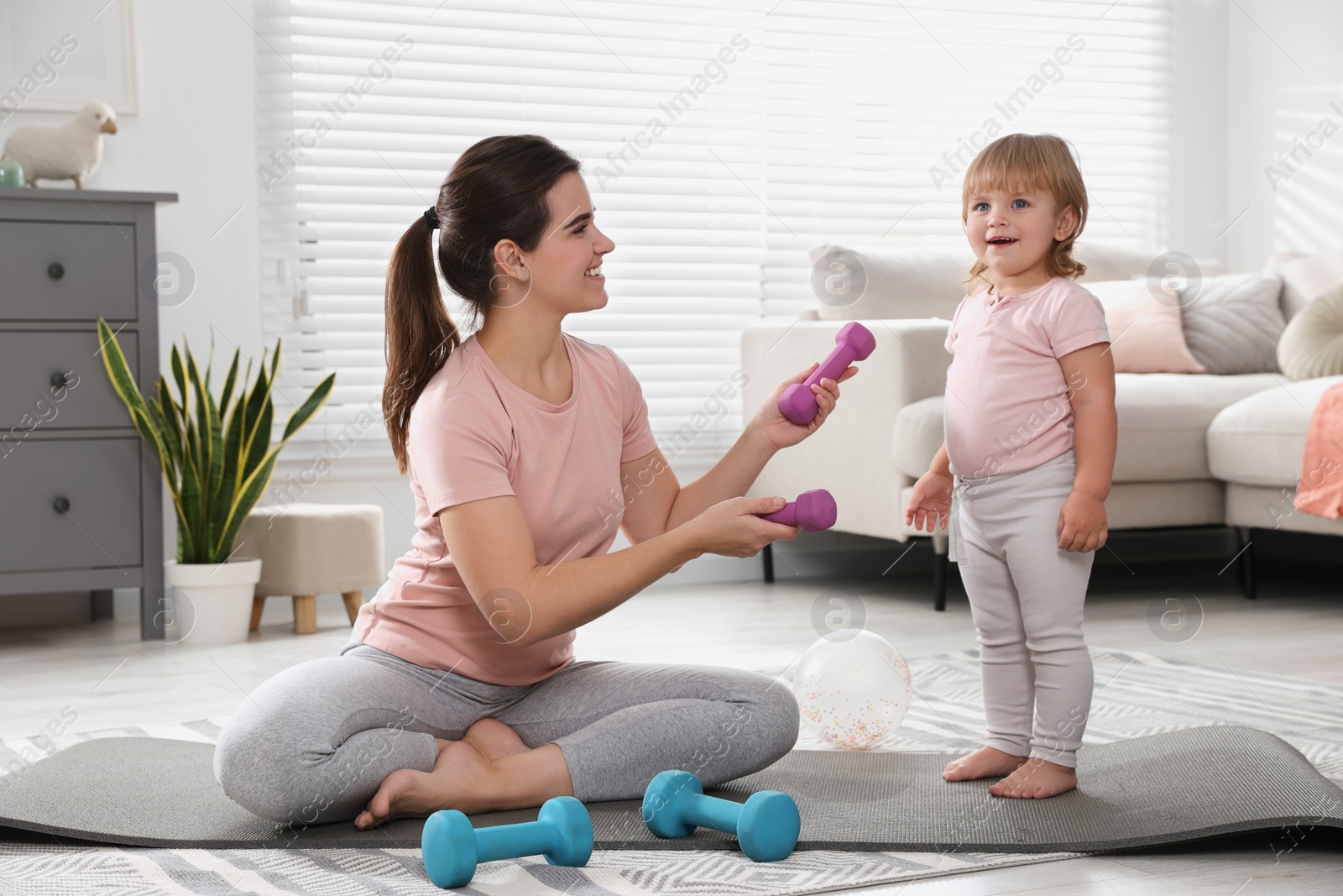 Photo of Mother and her daughter with dumbbells at home