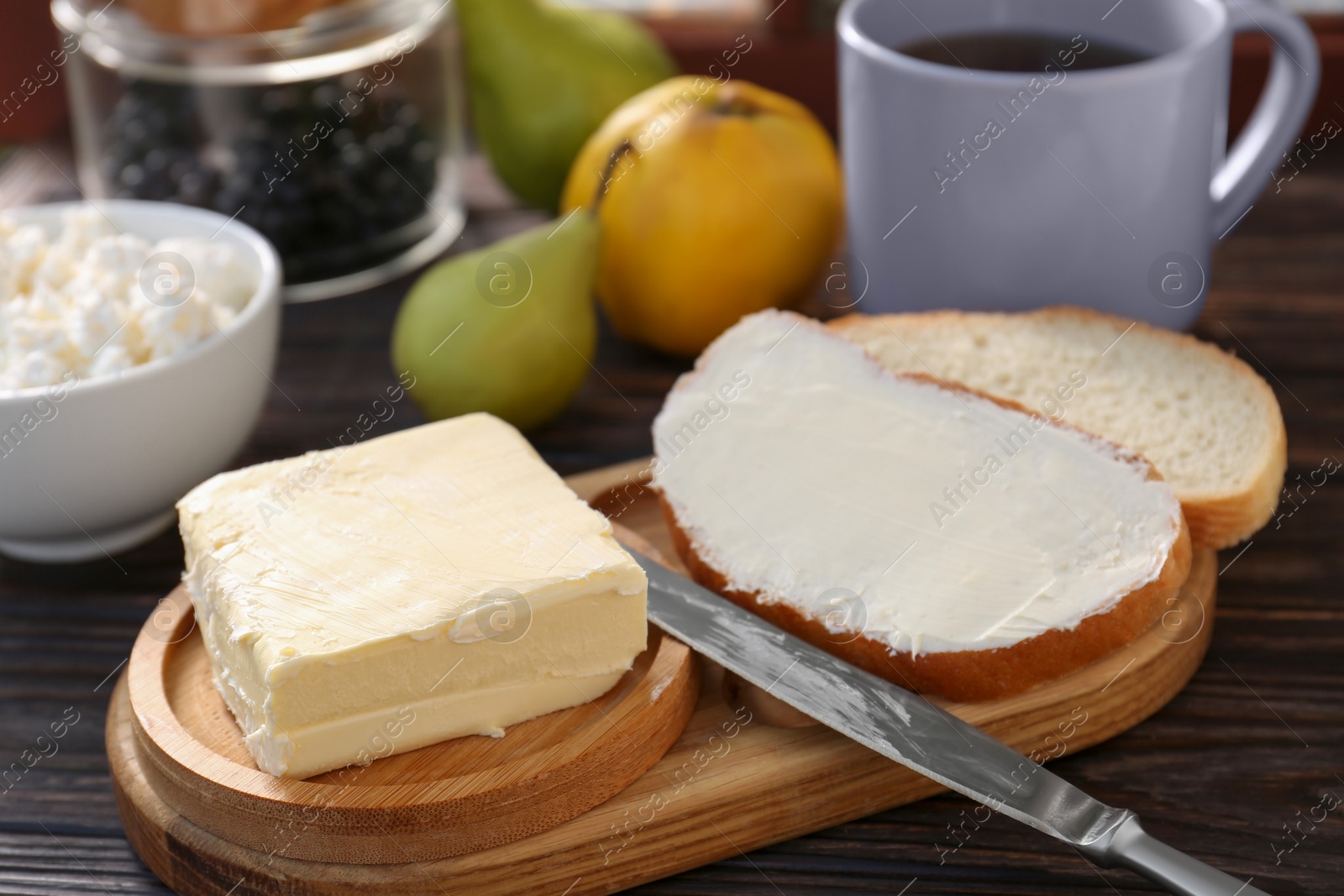 Photo of Tasty homemade butter, bread slices and tea on wooden table