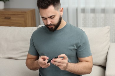 Diabetes test. Man checking blood sugar level with lancet pen at home