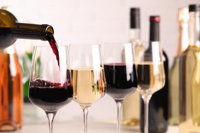 Photo of Pouring red wine from bottle into glass, closeup