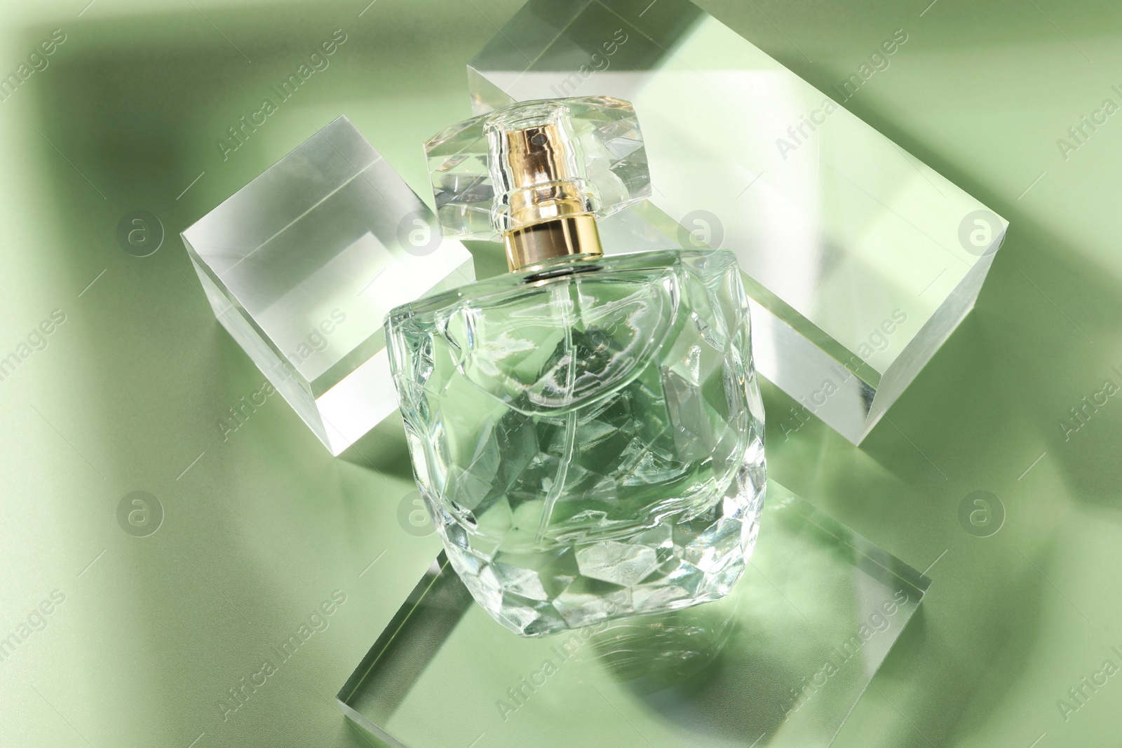 Photo of Stylish presentation of luxury perfume in sunlight on olive background, above view