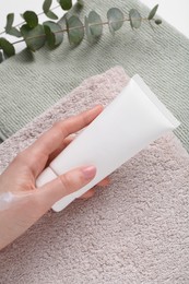 Woman with tube of cream against towels, closeup