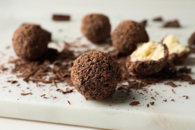 Photo of Many delicious chocolate truffles on white board, closeup