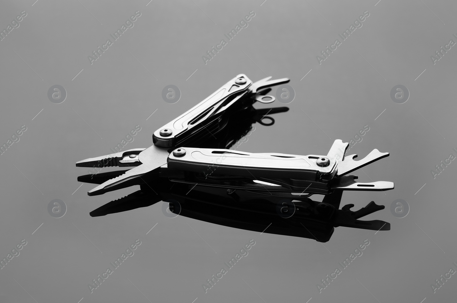 Photo of Compact portable metallic multitool on grey table