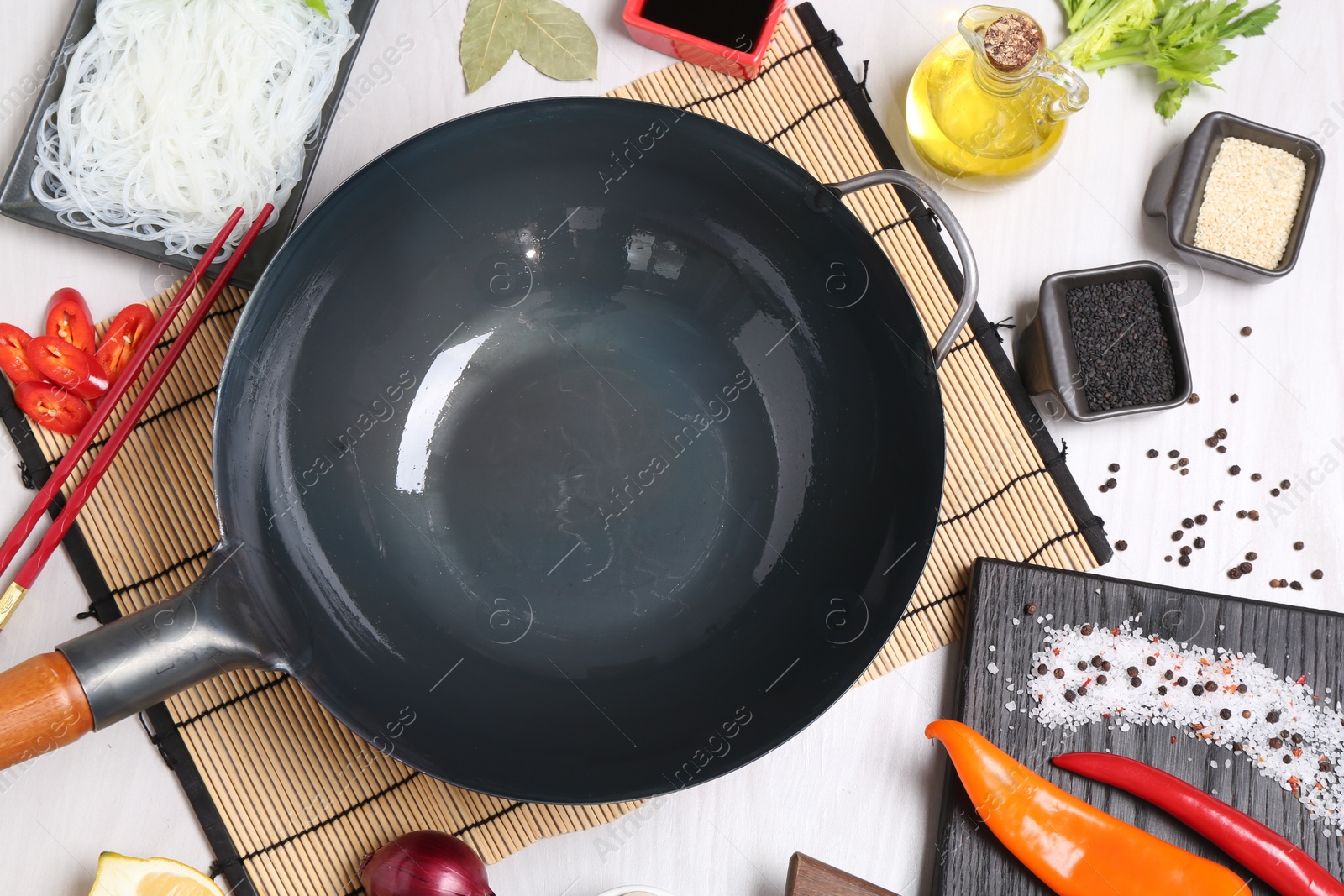 Photo of Wok, chopsticks and different products on white wooden table, flat lay