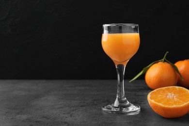 Delicious tangerine liqueur and fresh fruits on grey table, space for text