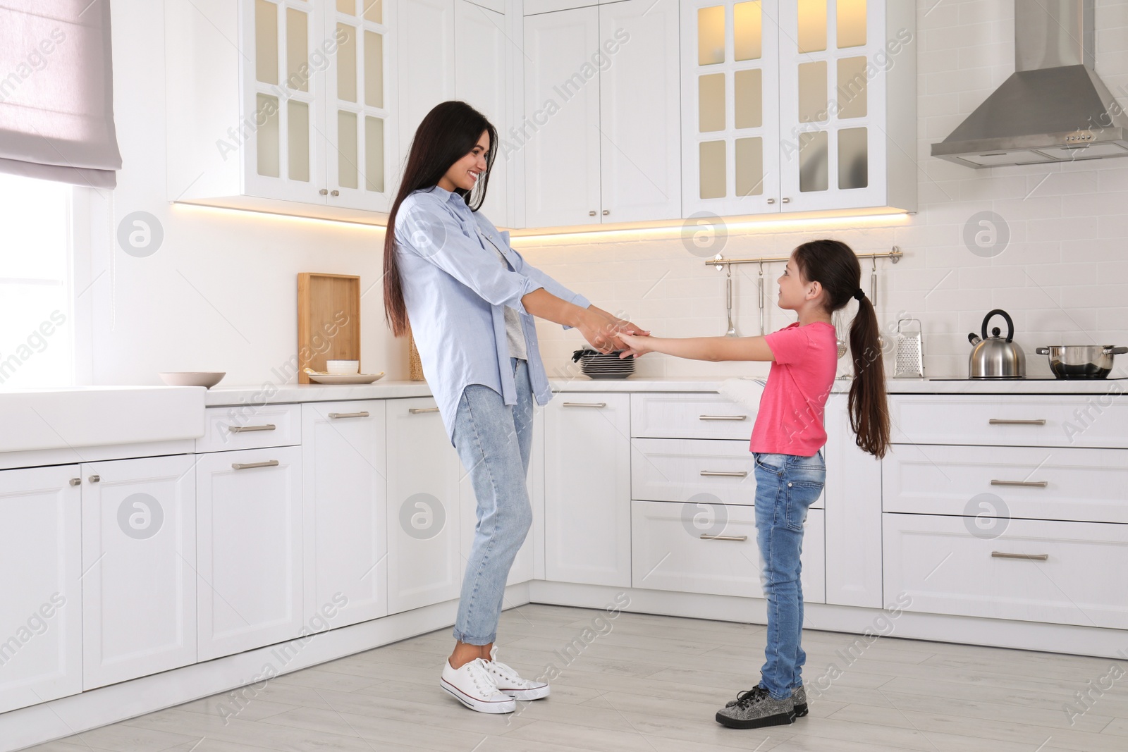 Photo of Happy mother and daughter dancing together in kitchen. Single parenting