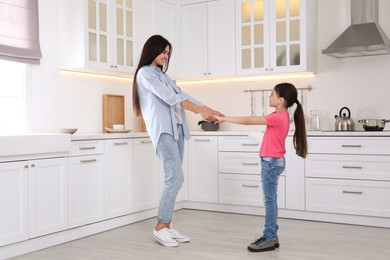 Happy mother and daughter dancing together in kitchen. Single parenting