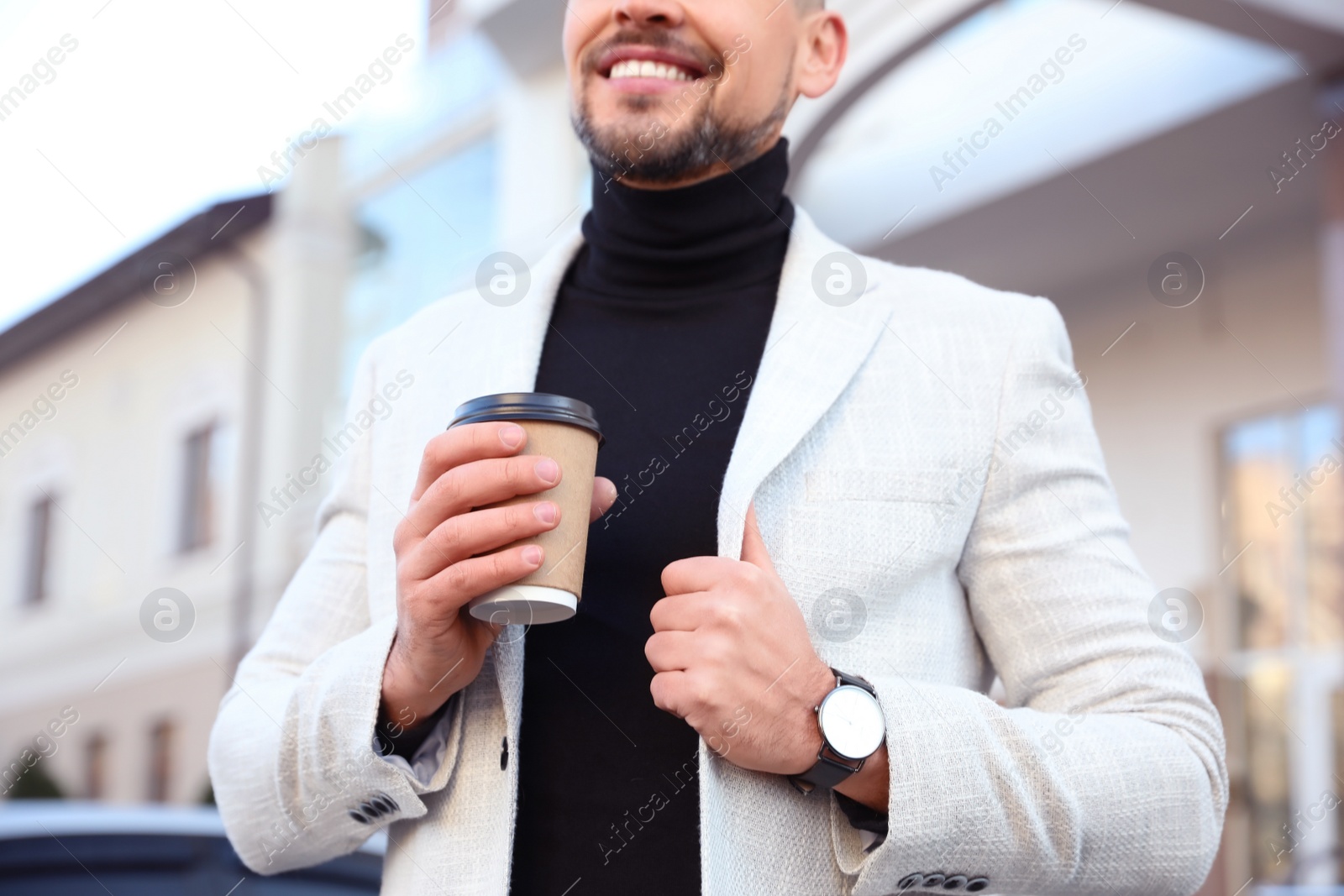 Photo of Businessman with cup of coffee on city street in morning, closeup