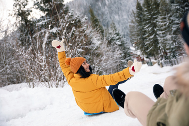 Photo of Couple having fun and sledding on snow. Winter vacation