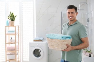 Happy man with laundry basket in bathroom