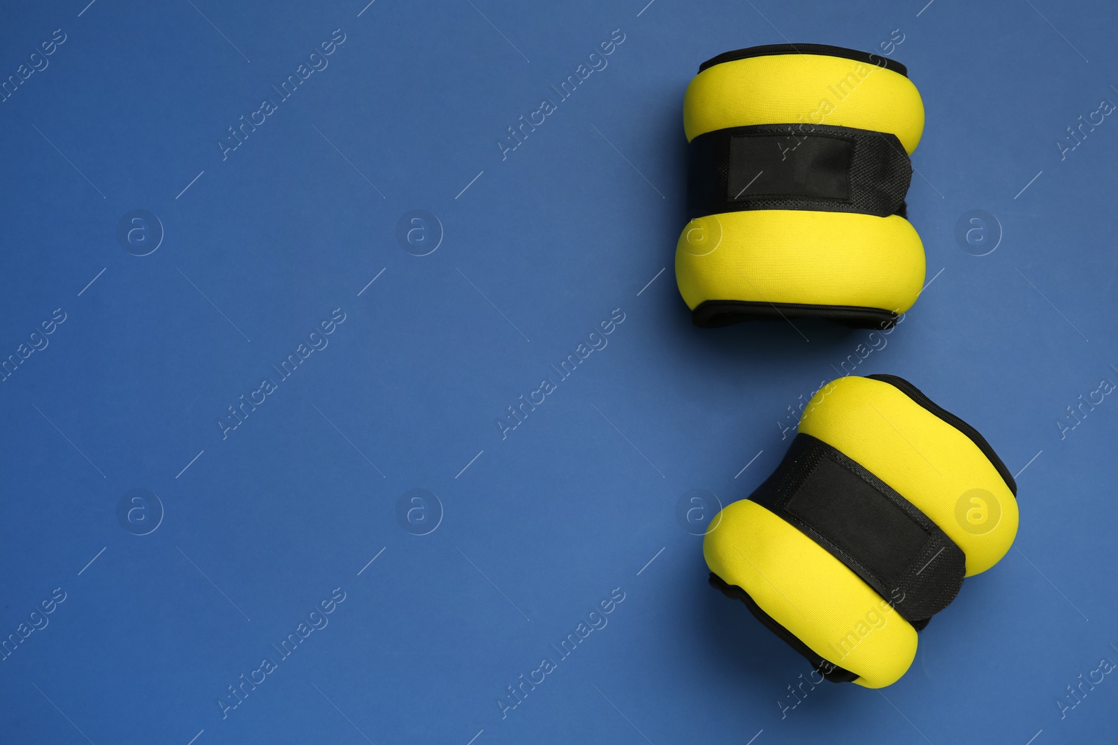 Photo of Yellow weighting agents on blue background, flat lay. Space for text