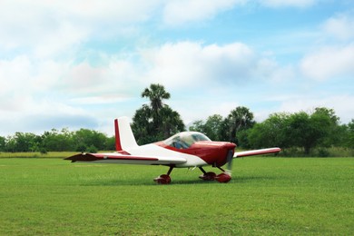 Ultralight aircraft on green grass near trees