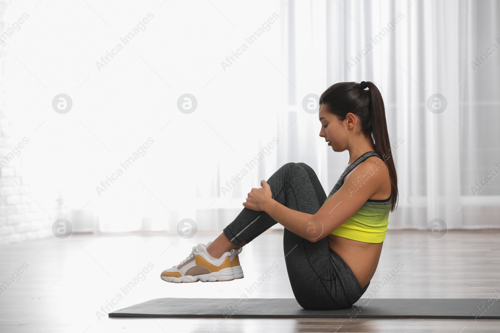 Photo of Young woman in fitness clothes doing exercise at home. Space for text