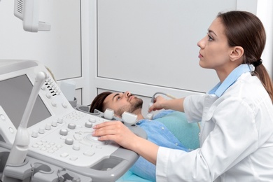 Photo of Doctor conducting ultrasound examination of patient's neck in clinic