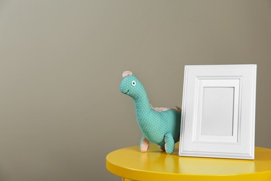Photo frame and toy for baby room interior on table against grey background