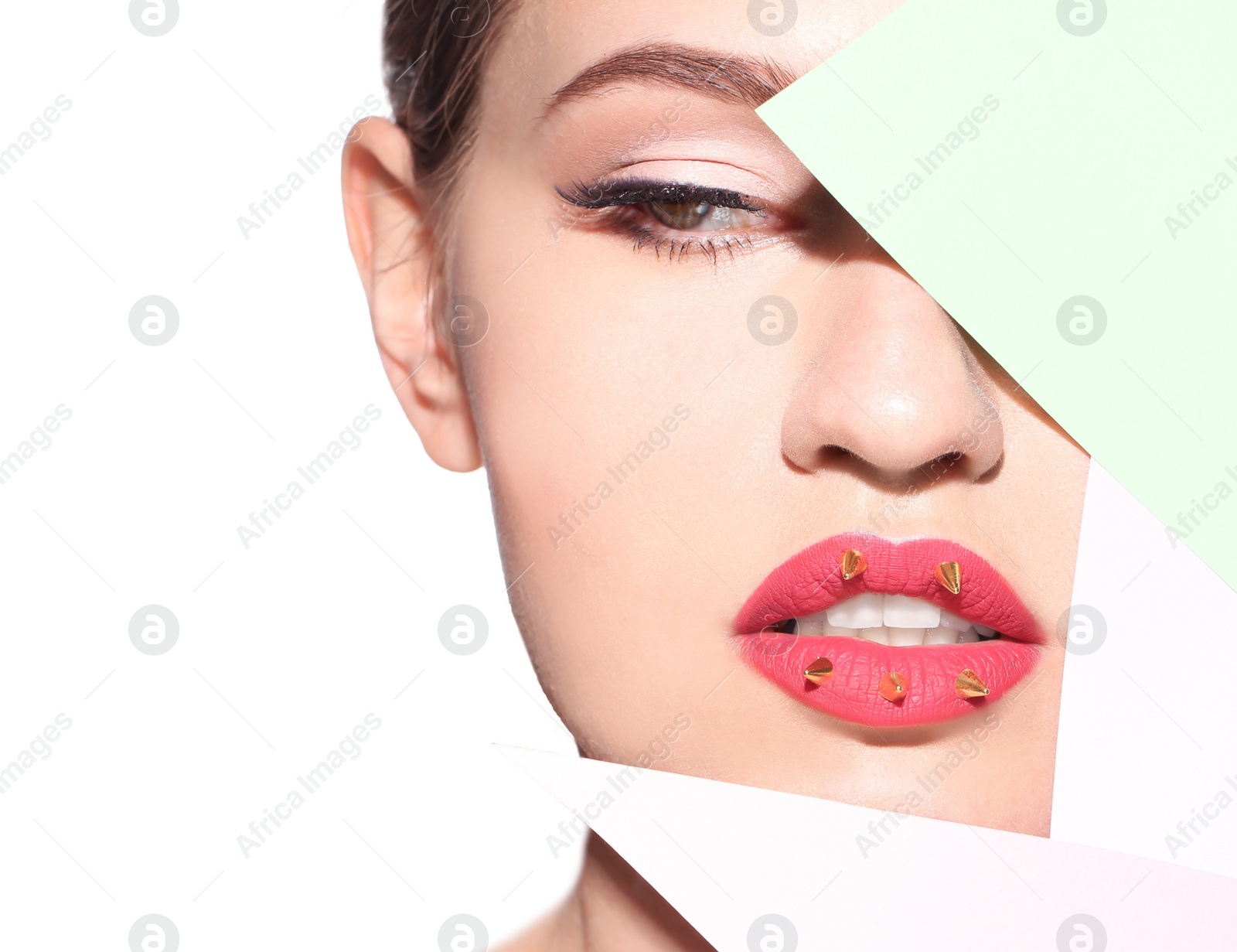 Photo of Beautiful young model with decorative spikes on lips and paper against white background