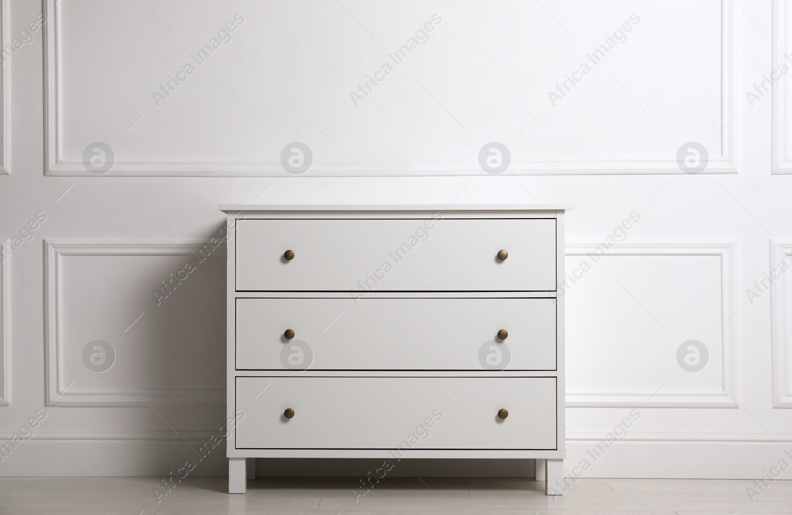 Photo of Stylish chest of drawers near white wall indoors
